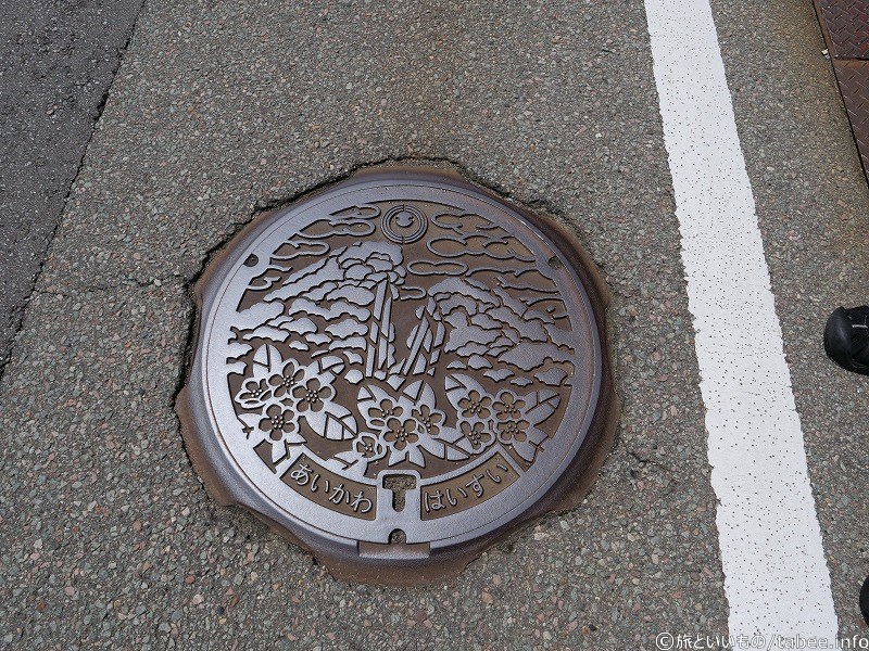 相川のマンホールは「道遊の割戸」と「マルバシャリンバイ」